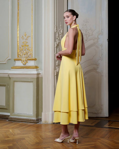 Woman in a yellow dress standing in an elegant interior setting