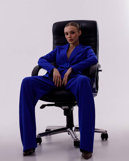 Person wearing a blue suit sitting on a black office chair against a white background