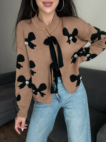 Person wearing a brown sweater with black bow designs and light blue jeans.