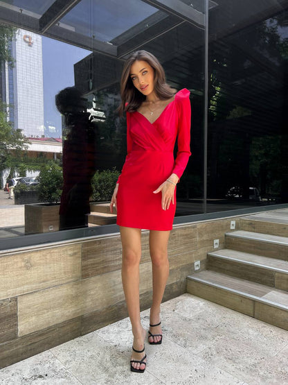 Woman in a red dress standing outdoors with a modern building in the background