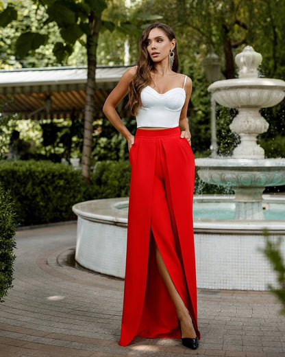 Woman in a white top and red pants standing in front of a fountain