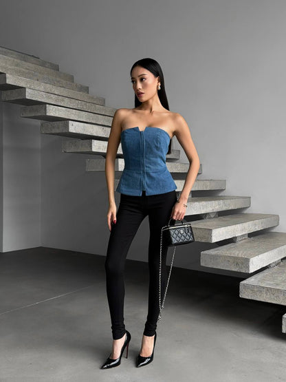 Woman in a blue top and black pants standing in front of a modern staircase.
