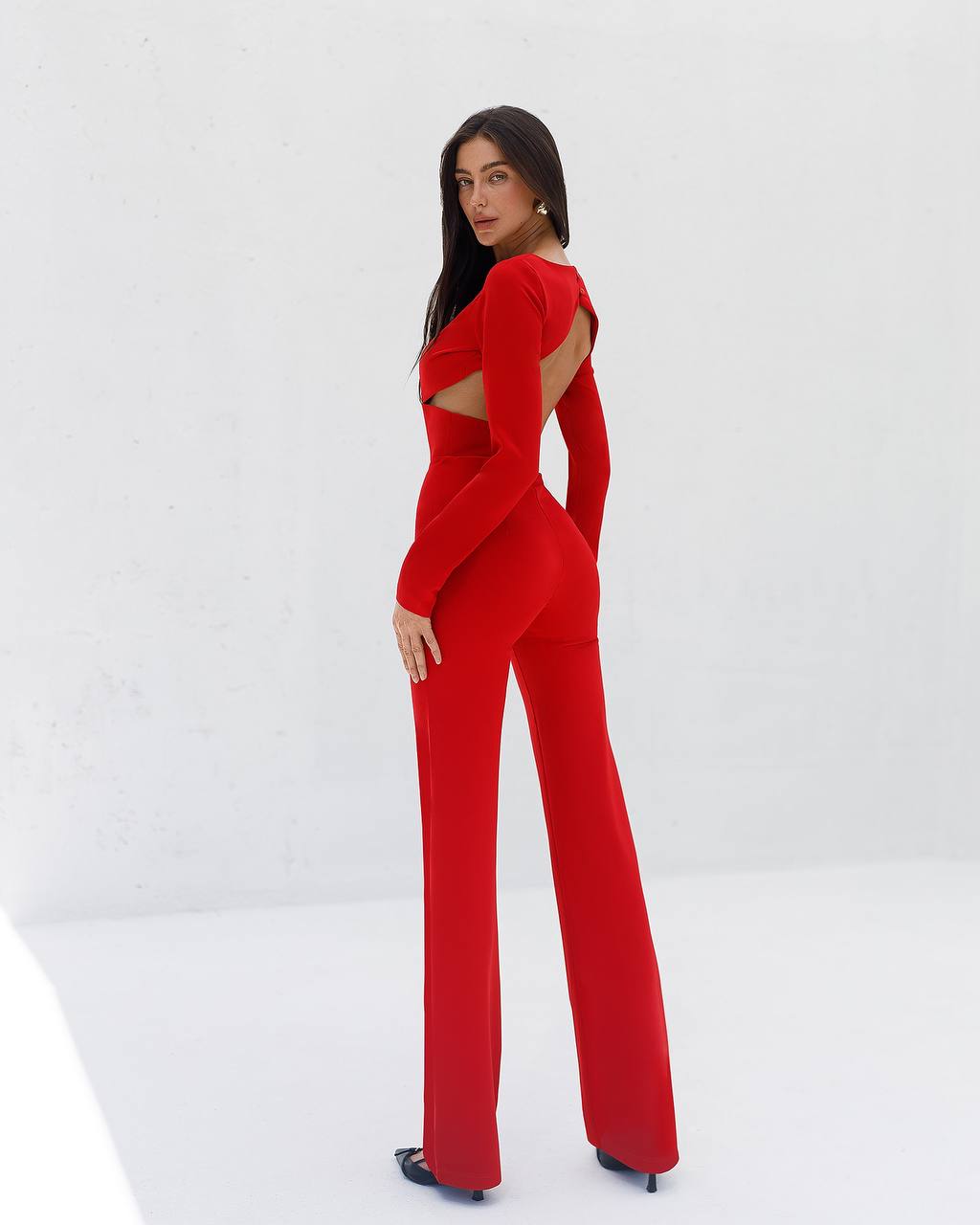 Woman wearing a red jumpsuit with cut-out design on a white background