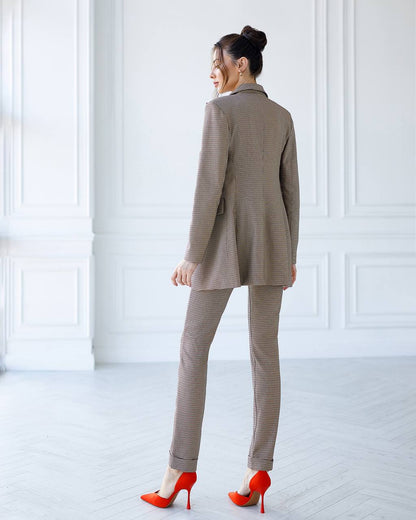Woman wearing a beige suit with red high heels in a white room