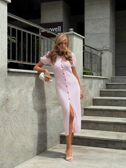Woman in a pink dress standing on a staircase with a building in the background