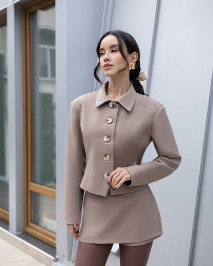 Woman wearing a beige suit standing in front of a modern building.