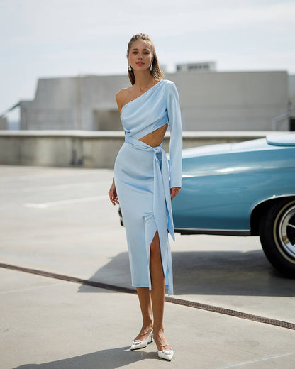 Woman in a light blue dress standing on a rooftop with a vintage car in the background