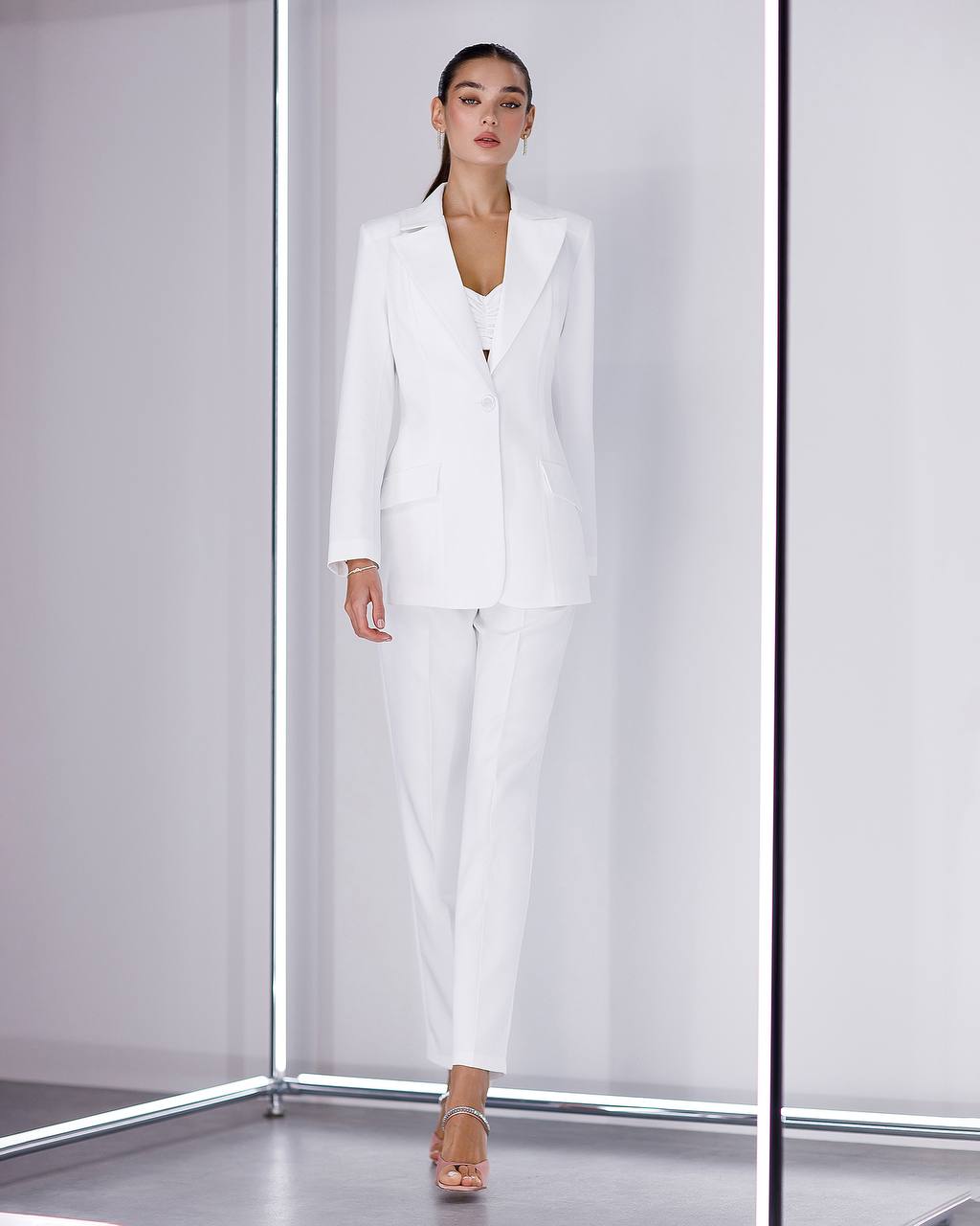 Woman wearing a white suit standing in front of a white background