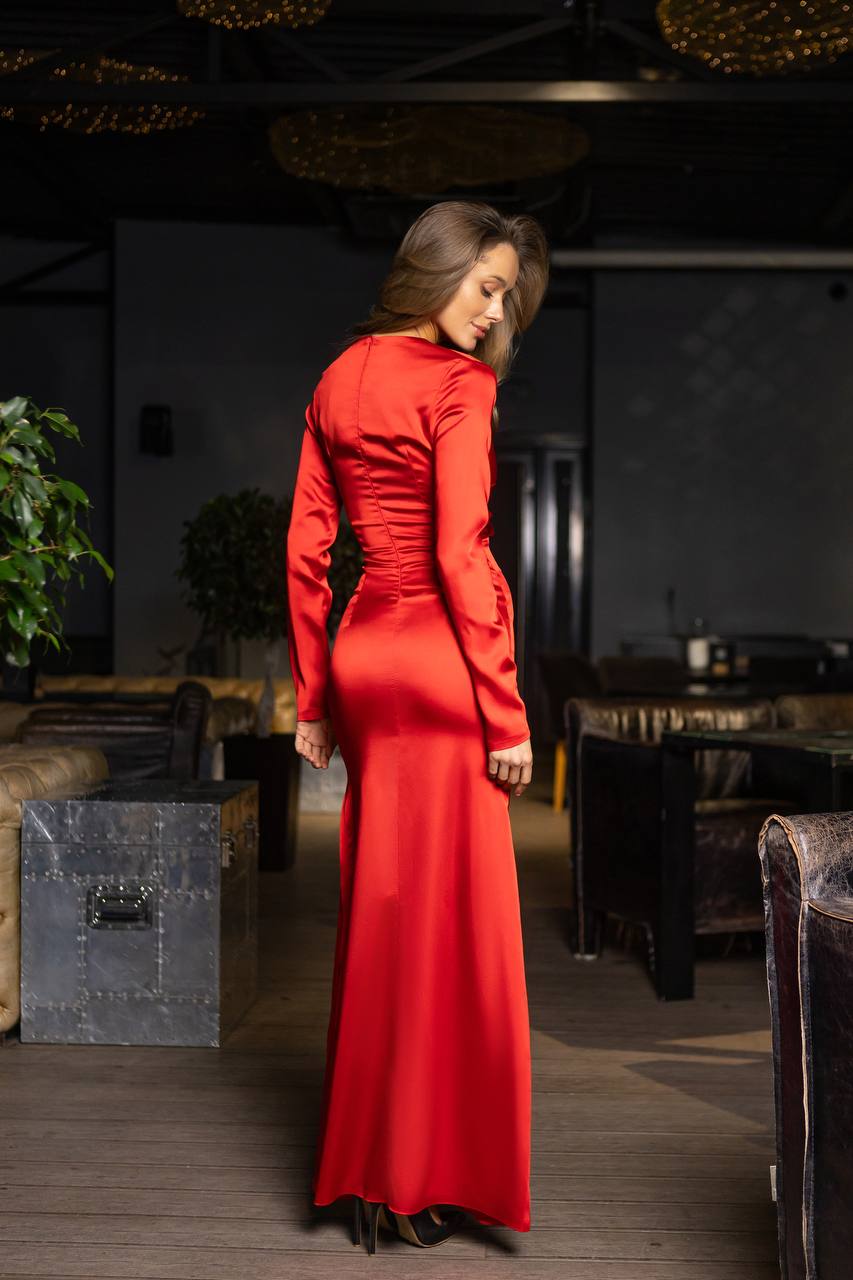 Woman in a red dress standing in an indoor setting with furniture and decor.