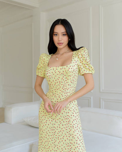 Woman wearing a yellow floral dress in a minimalistic room.