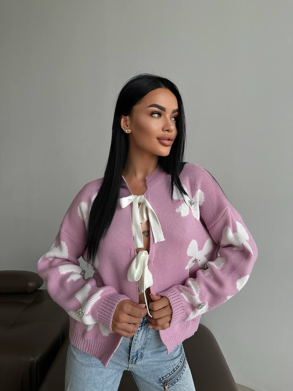 Woman wearing a pink sweater with white patterns against a plain background