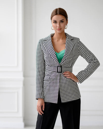 Woman wearing a black and white checkered blazer over a green top and black pants on a white background
