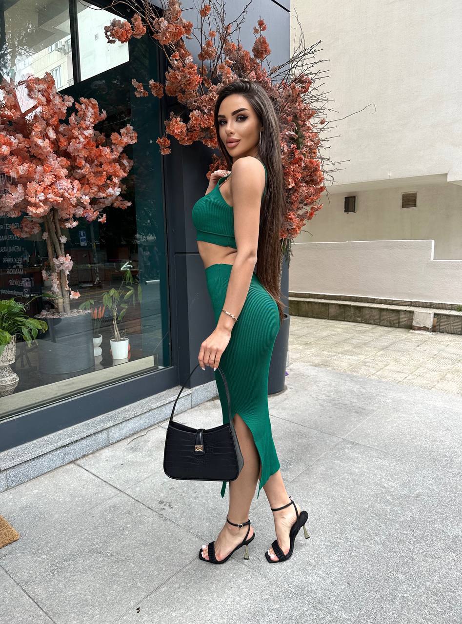 Woman in a green dress standing outdoors with decorative flowers in the background