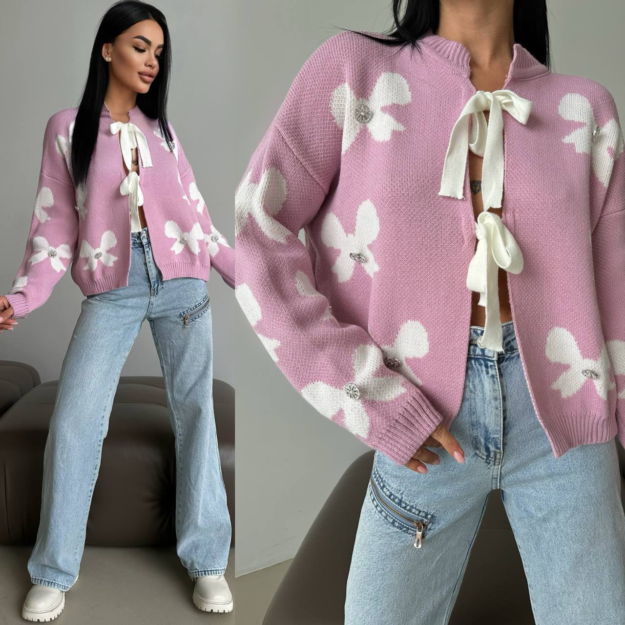 Pink sweater with white floral patterns and ribbons worn by a person, sitting on a gray couch.