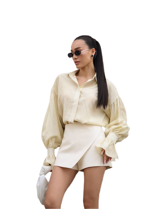 Person wearing a cream-colored outfit with sunglasses on a white background