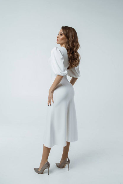 Woman wearing a white dress with puffed sleeves on a light gray background