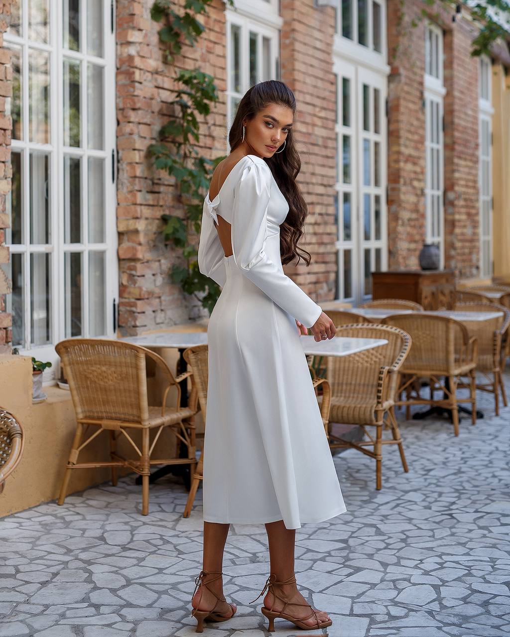 Woman in a white dress standing in an outdoor cafe setting