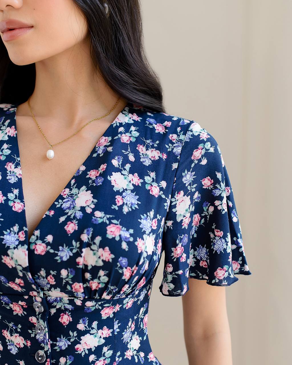 Woman wearing a navy floral dress with a neutral background