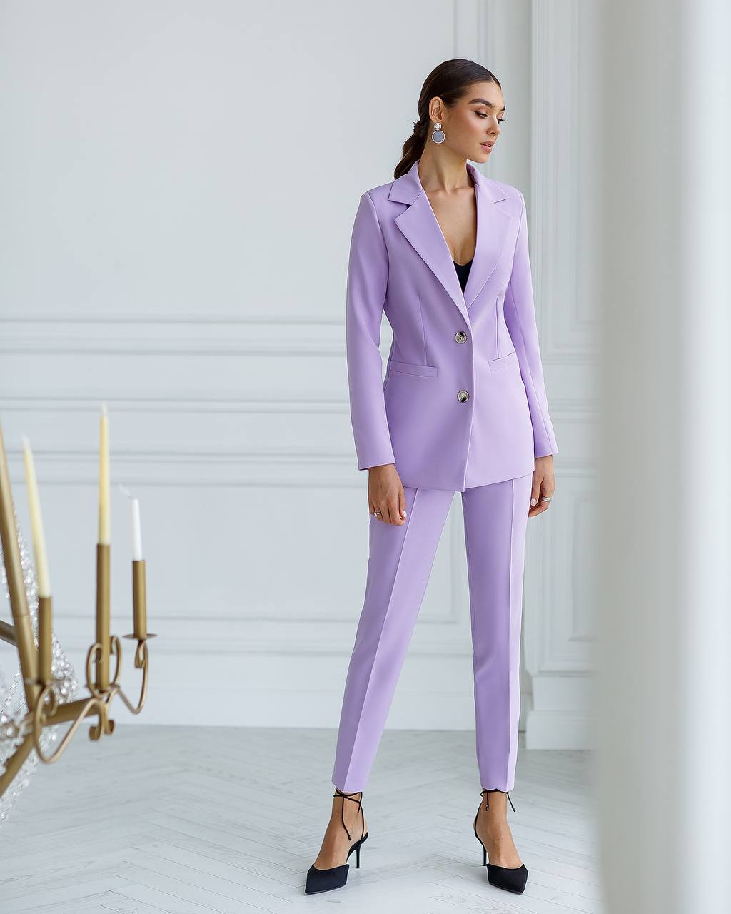 Woman wearing a lavender suit in a minimalistic room.