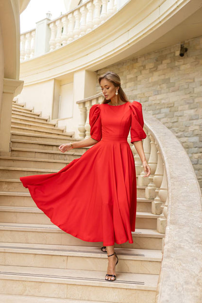 Woman in a red dress standing on a staircase with classical architecture.