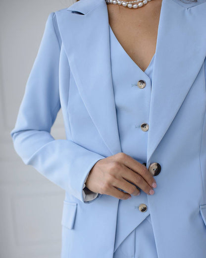 Light blue suit with pearl necklace on a neutral background