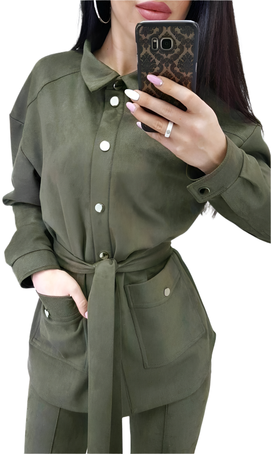 Person wearing a green outfit with a belt, holding a phone with a leopard print case.