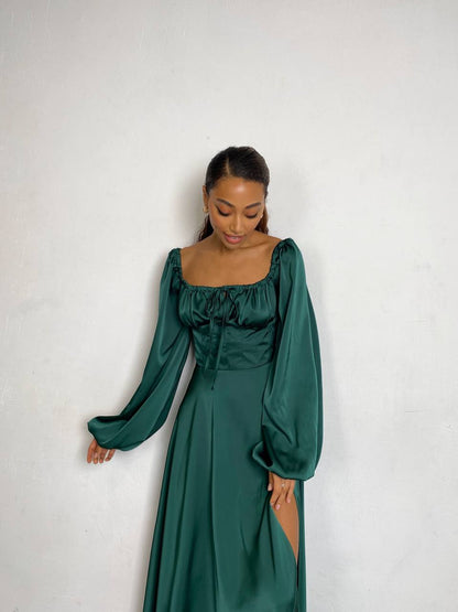 Woman wearing a green dress with long sleeves against a white background