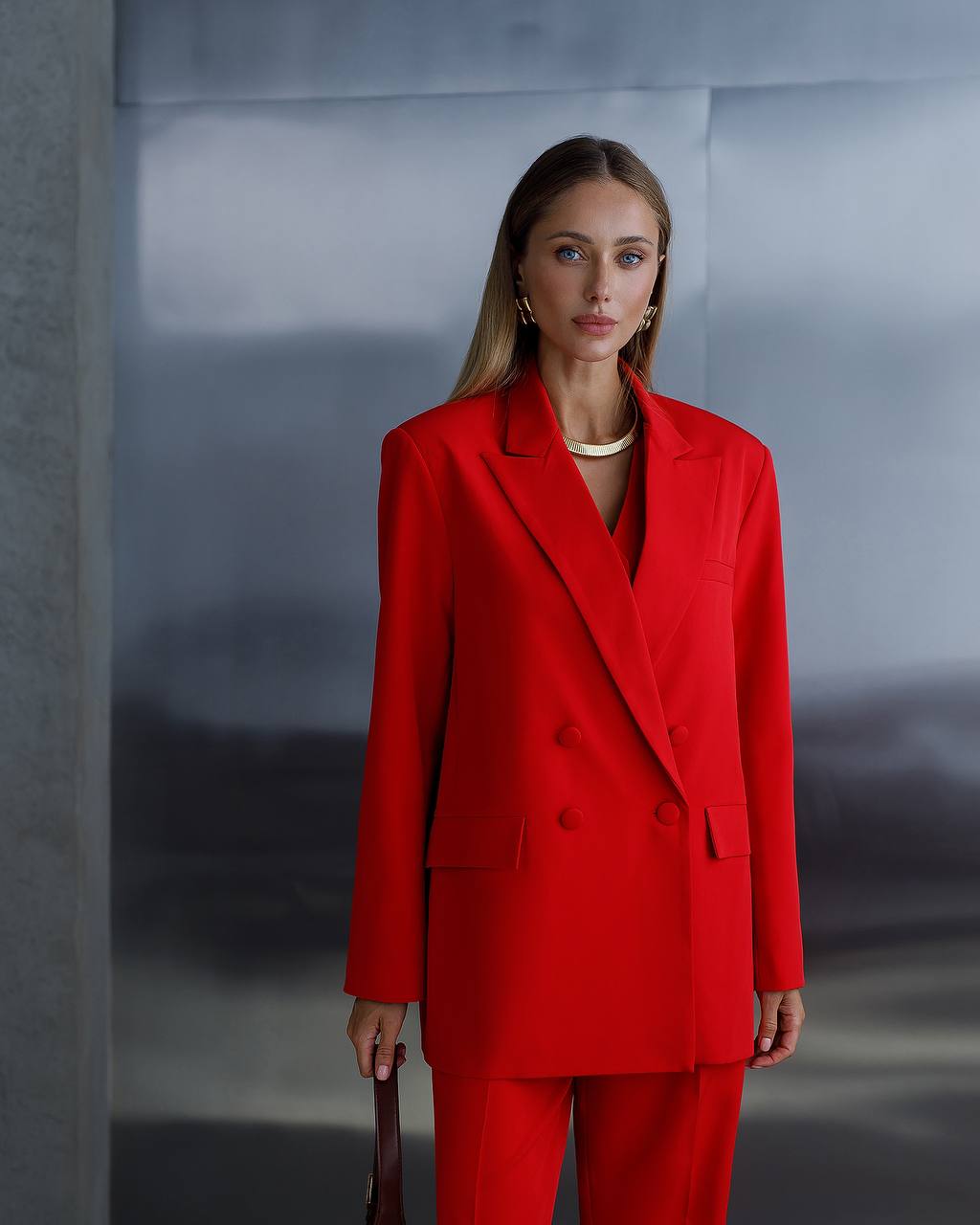 Woman wearing a red suit against a gray background