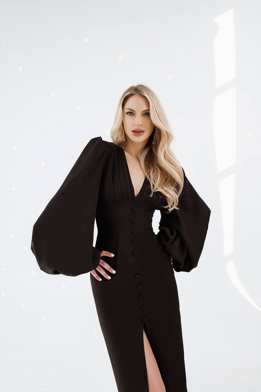 Woman wearing a black dress with puffed sleeves on a white background