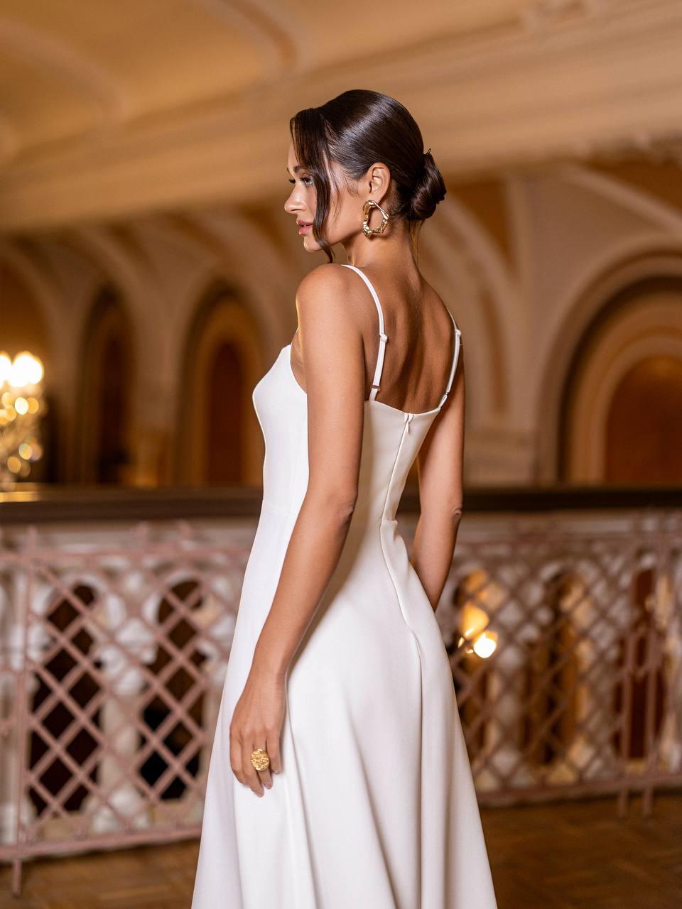 Woman in a white dress standing in an elegant indoor setting