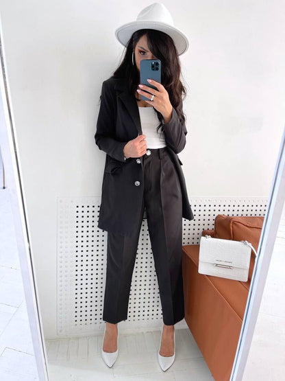 Person wearing a black suit and white hat taking a mirror selfie.