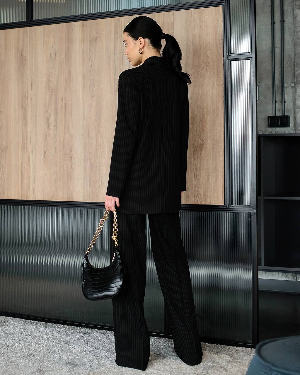 Person wearing a black outfit with a handbag in an indoor setting