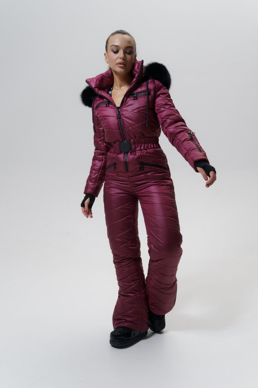 Person wearing a maroon snowsuit with black fur trim on a white background
