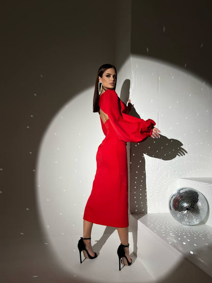 Woman in a red dress standing in a spotlight with a disco ball in the background