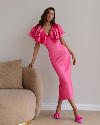 Woman wearing a pink dress with ruffled sleeves in a room with a beige sofa.