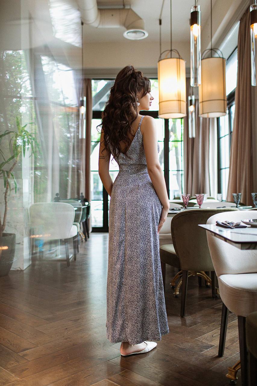 Woman in a long, patterned dress standing in a modern restaurant.