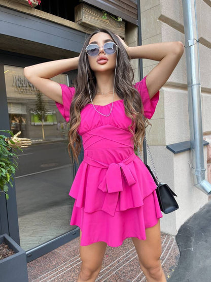 Woman in a bright pink dress posing outdoors.
