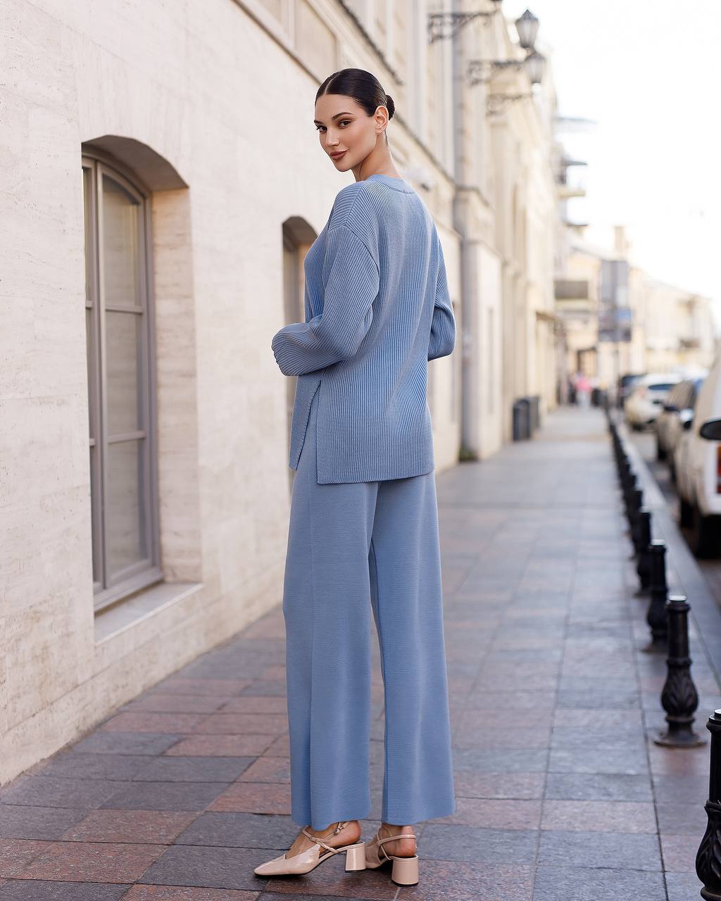 Woman in a light blue suit standing on a city street.