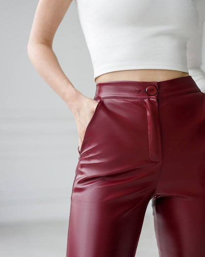 Maroon leather pants worn by a person on a plain background