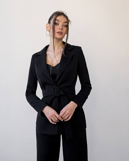 Woman wearing a black suit against a plain background