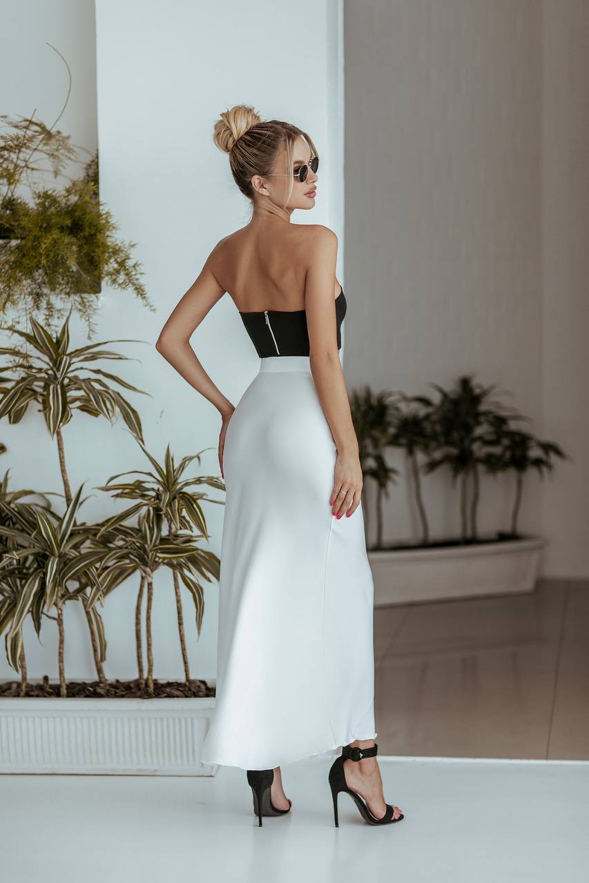 Woman in a black and white dress standing in a room with plants.