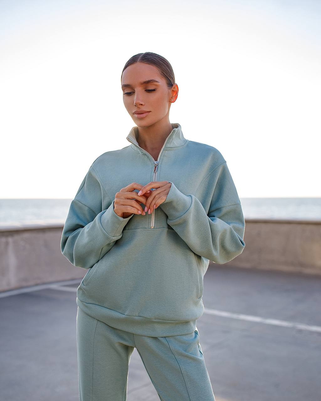 Woman wearing a light blue tracksuit standing on a rooftop with a cityscape background