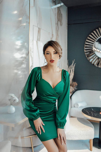 Woman in a green dress posing in an elegant interior setting
