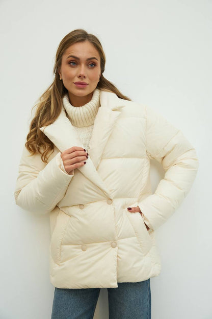 Woman wearing a cream puffer jacket against a white background
