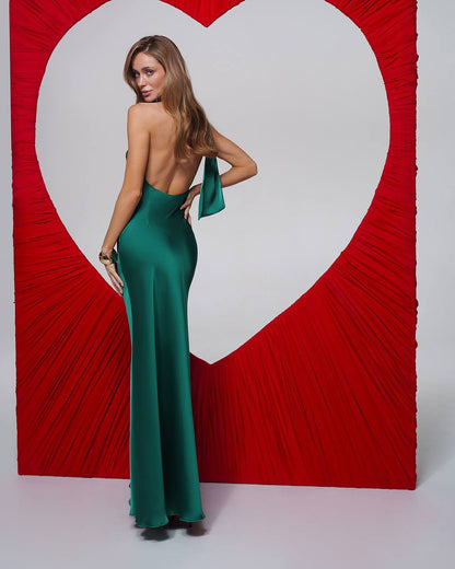 Woman in a green dress standing in front of a red heart-shaped backdrop