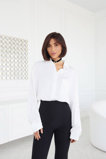 Woman wearing a white blouse and black pants in a minimalistic setting