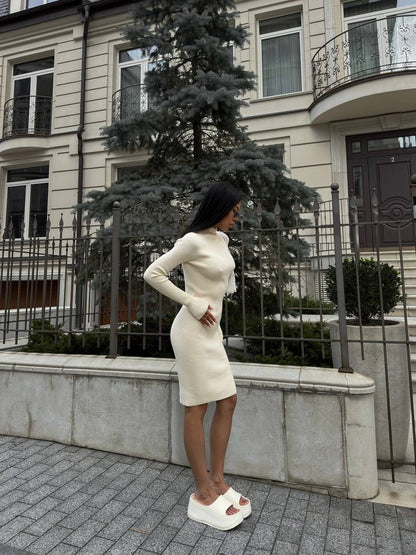 Woman in a white dress standing on a street with buildings and trees in the background