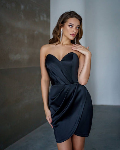 Woman wearing a black strapless dress against a neutral background