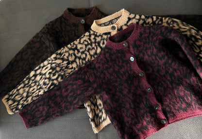 Two cardigans with leopard print sleeves on a gray surface