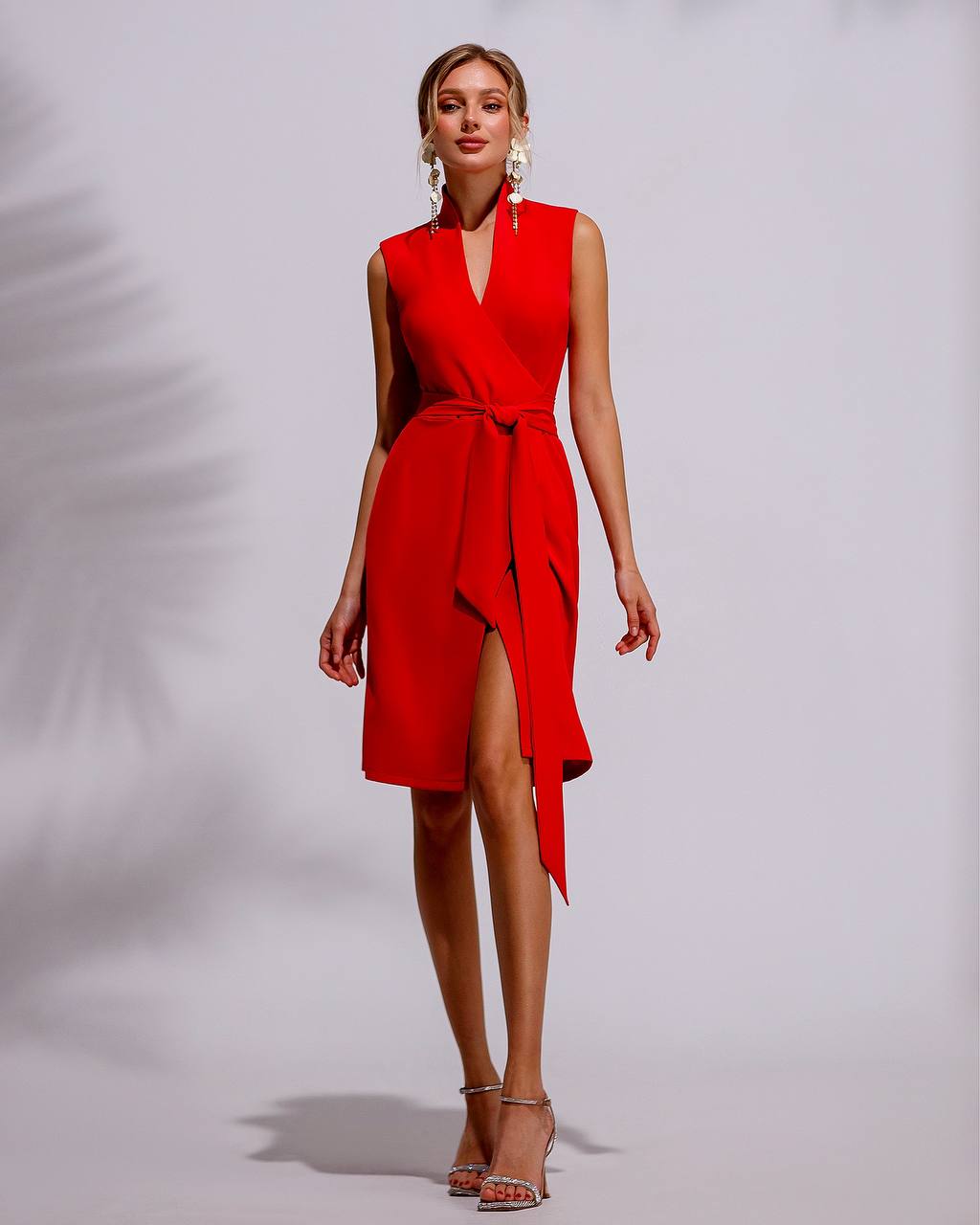 Red sleeveless dress with a belt and slit on a plain background